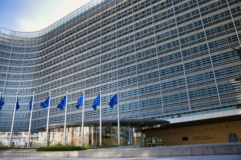 European Union flags in front of a glass-fronted building in Brussels